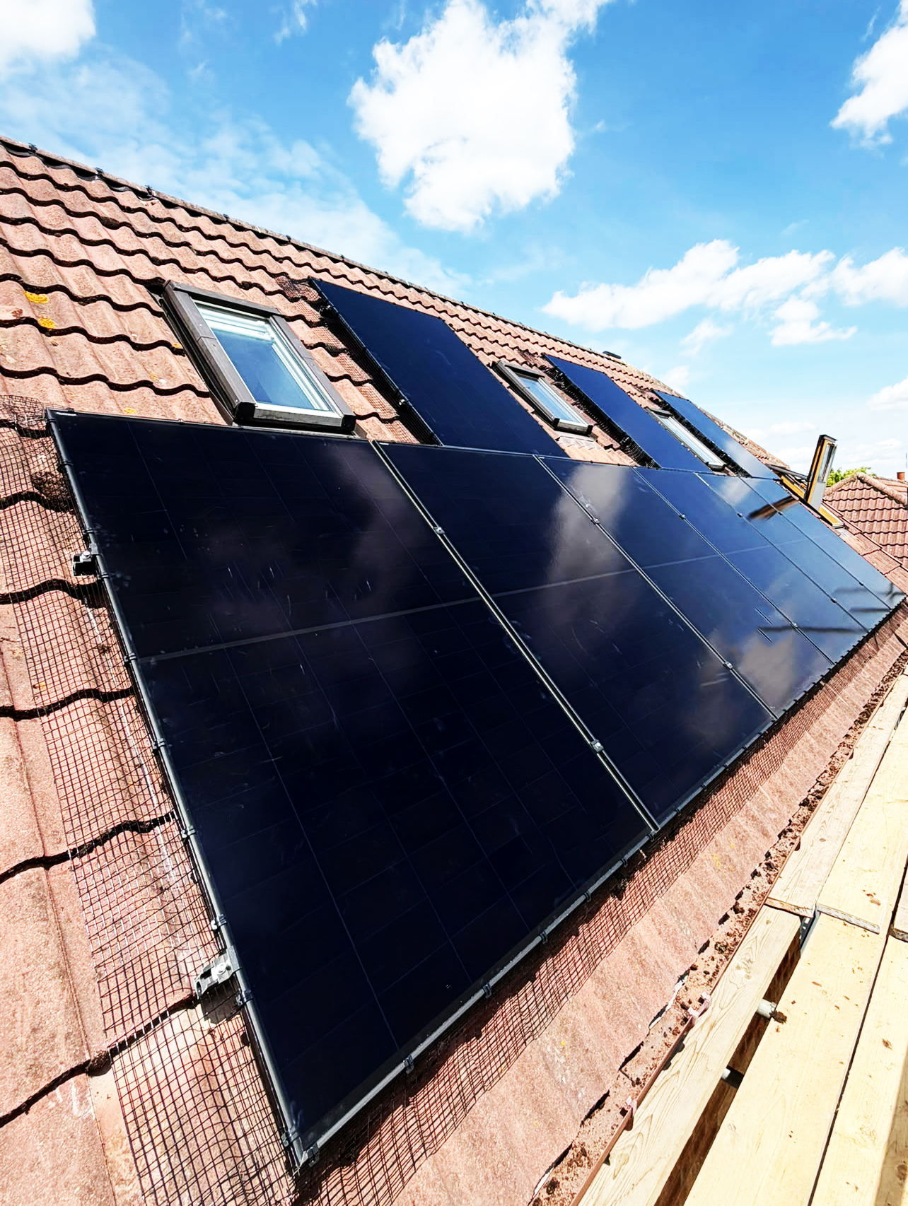 Black solar panles on an angles roof with blue sky in the background