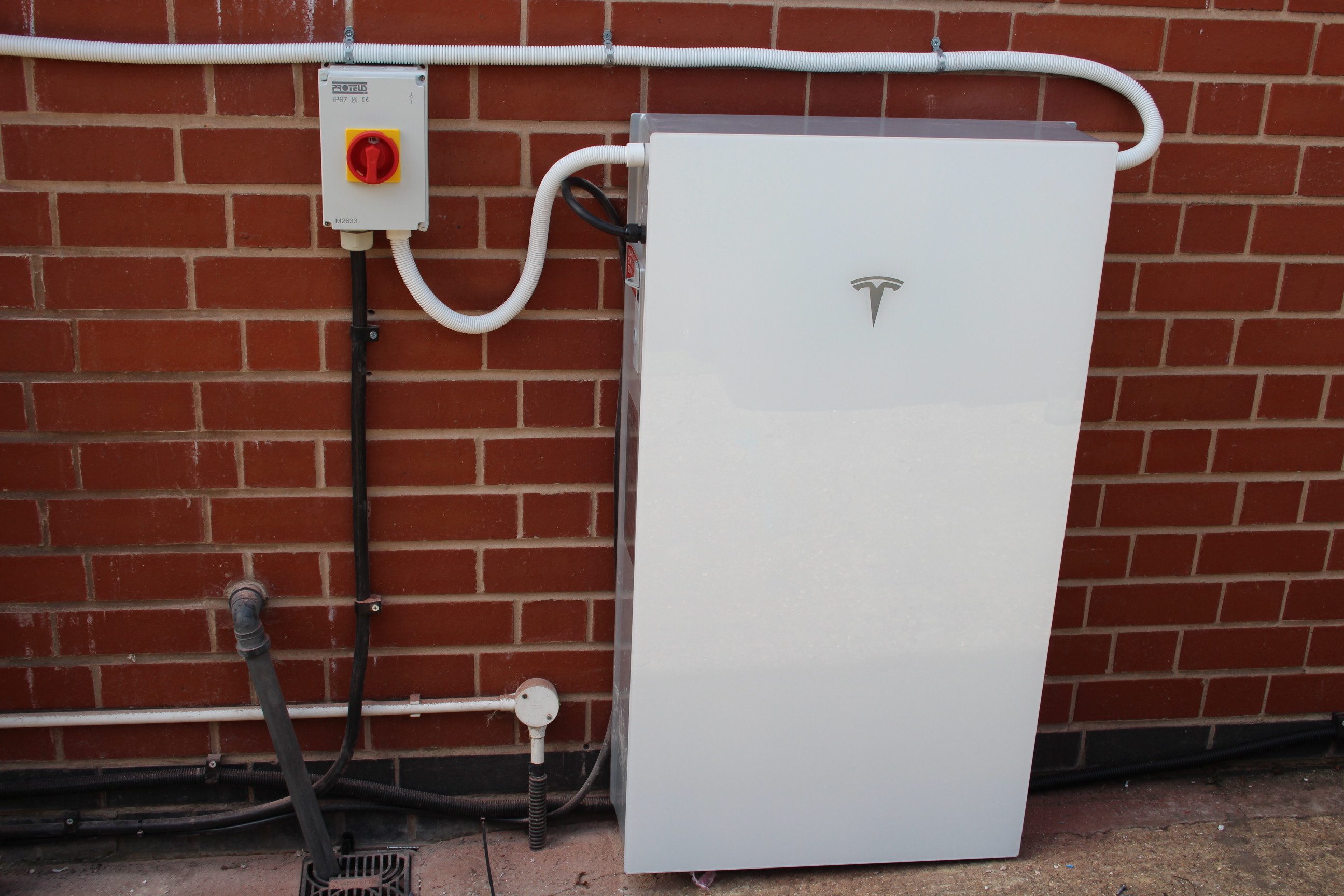 Picture of a Tesla Powerwall 3 fitted on the outside of a house on a brick wall