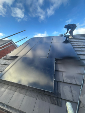 Black Solar Panels On a South Facing Roof with a Fitter Installing Bird Guard.