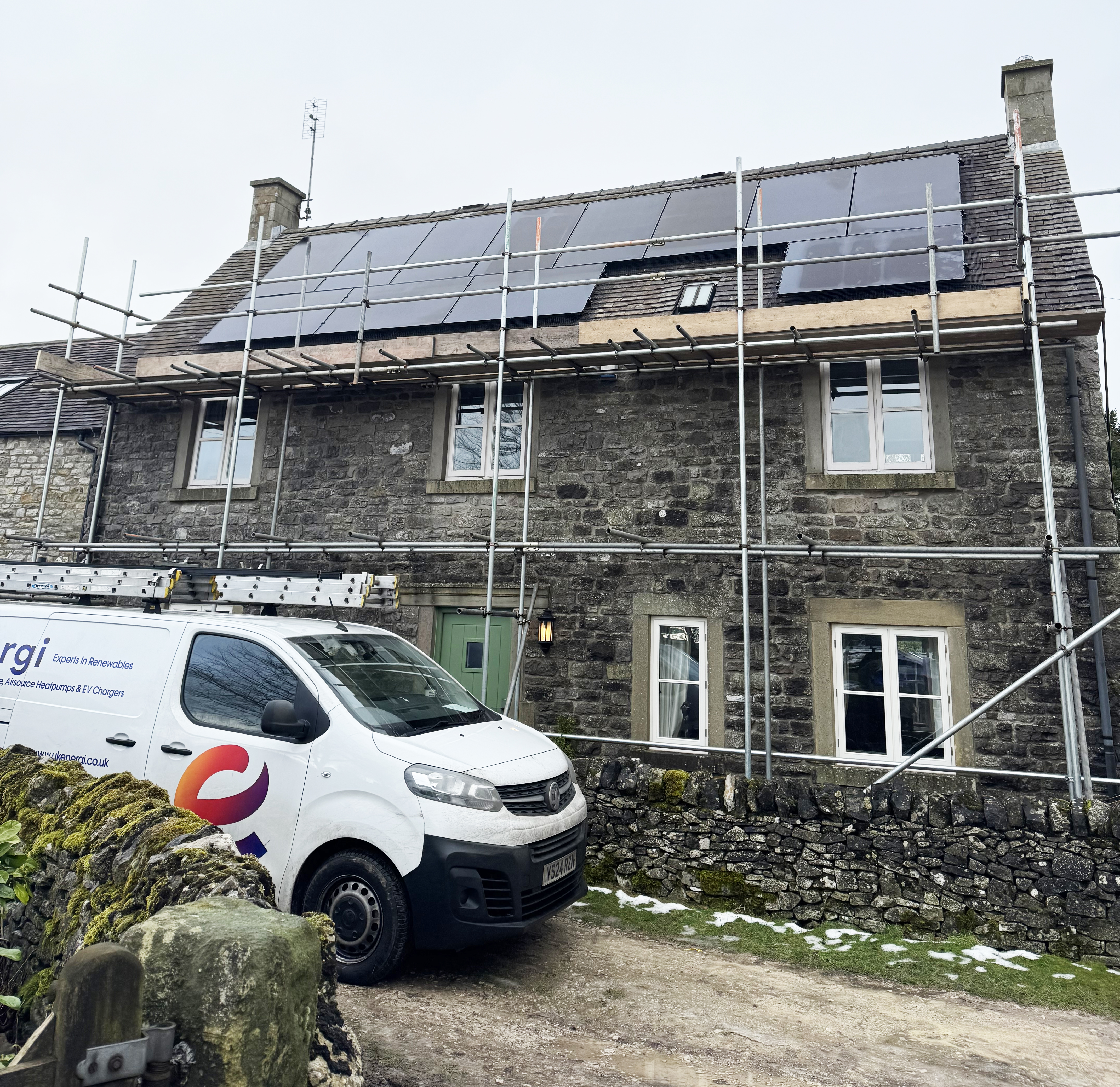 Detached house with scaffolding, having solar panels fitted with a UK Energi van outside.
